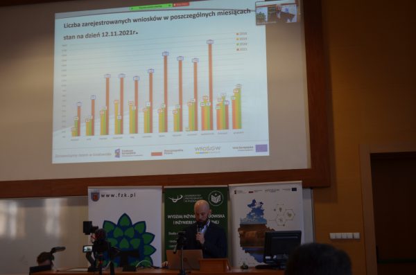 Maciej Kołowski, doradca energetyczny podczas prezentacji na temat Programu Czyste Powietrze. U góry widoczna prezentacja.