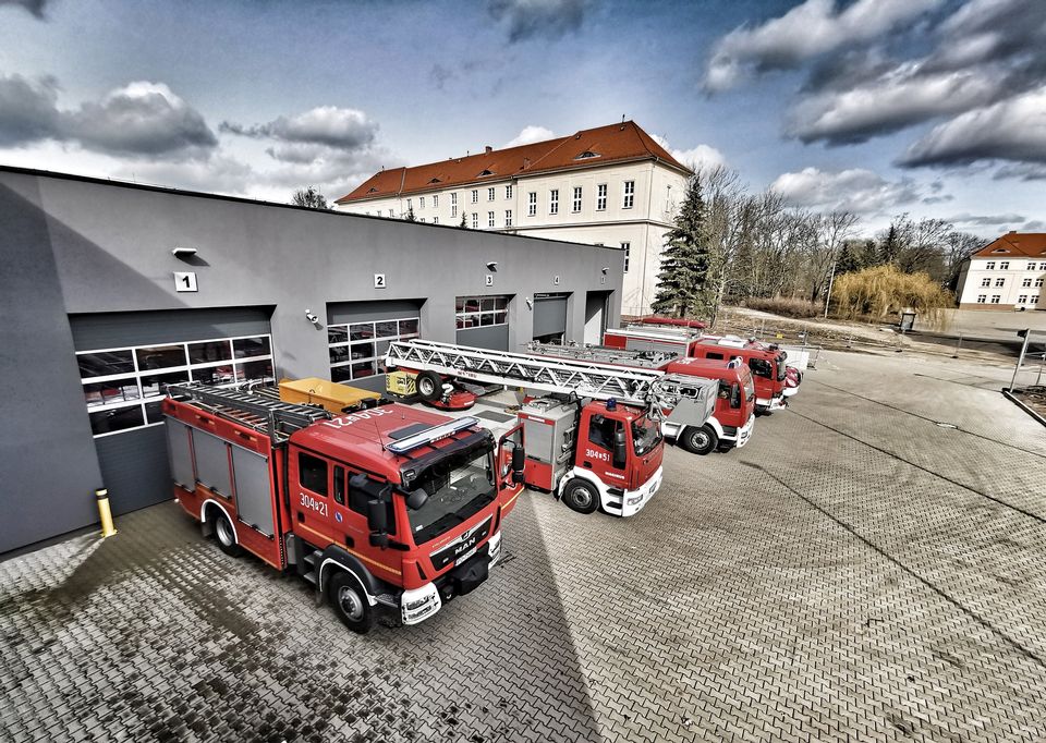Zdjęcie budynku straży pożarnej wraz ze stojącymi pojazdami