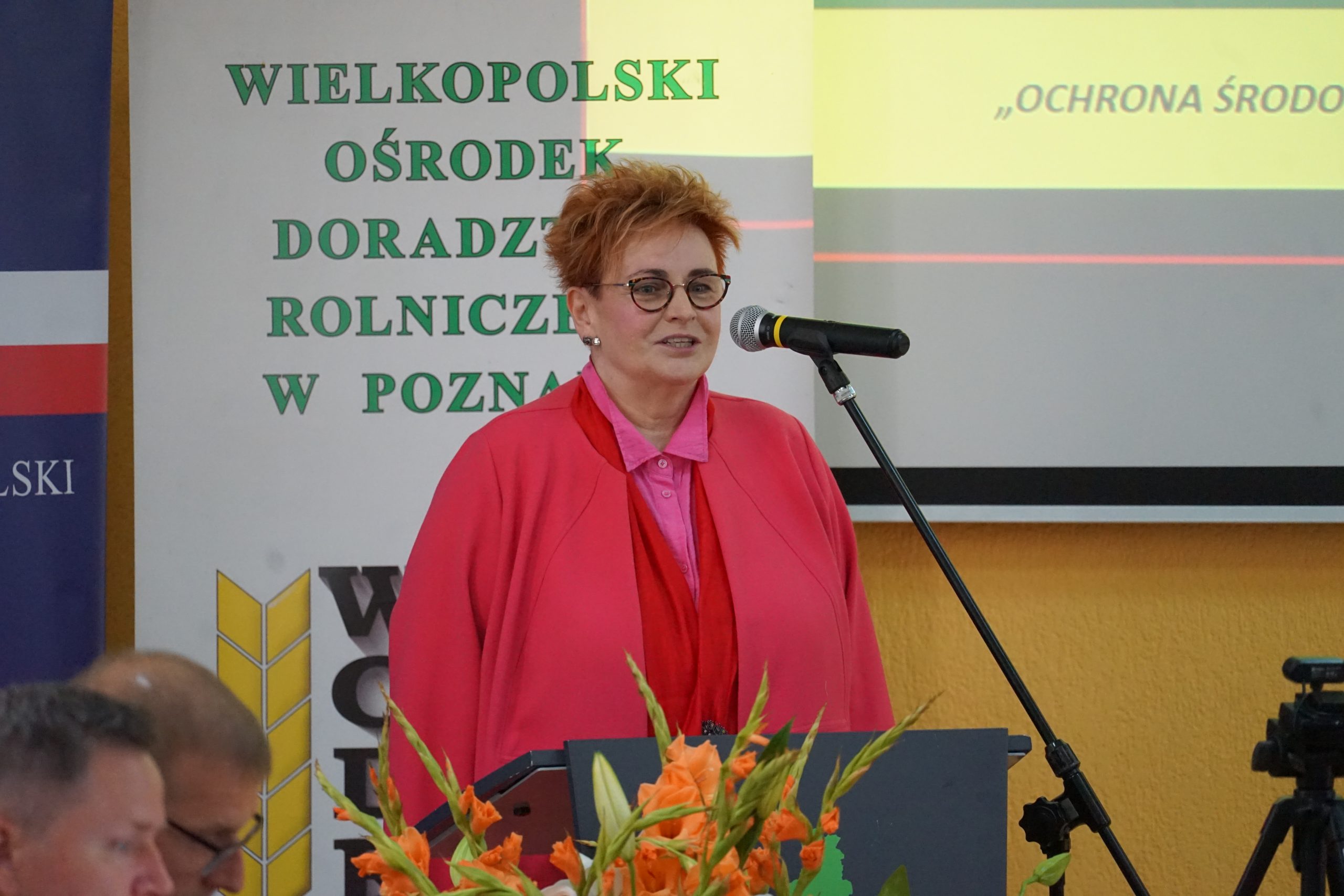 1 osoba stoi przy mównicy.