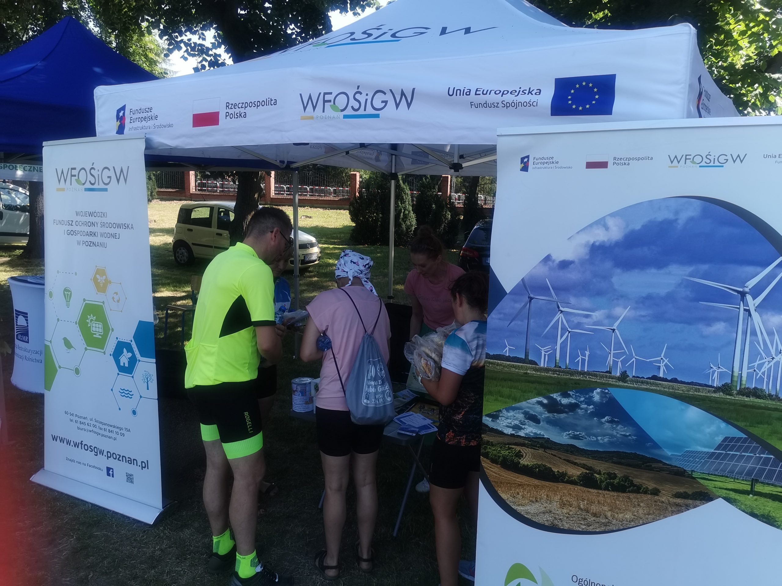 4 1 osoby stoją przy stoisku wystawienniczym.