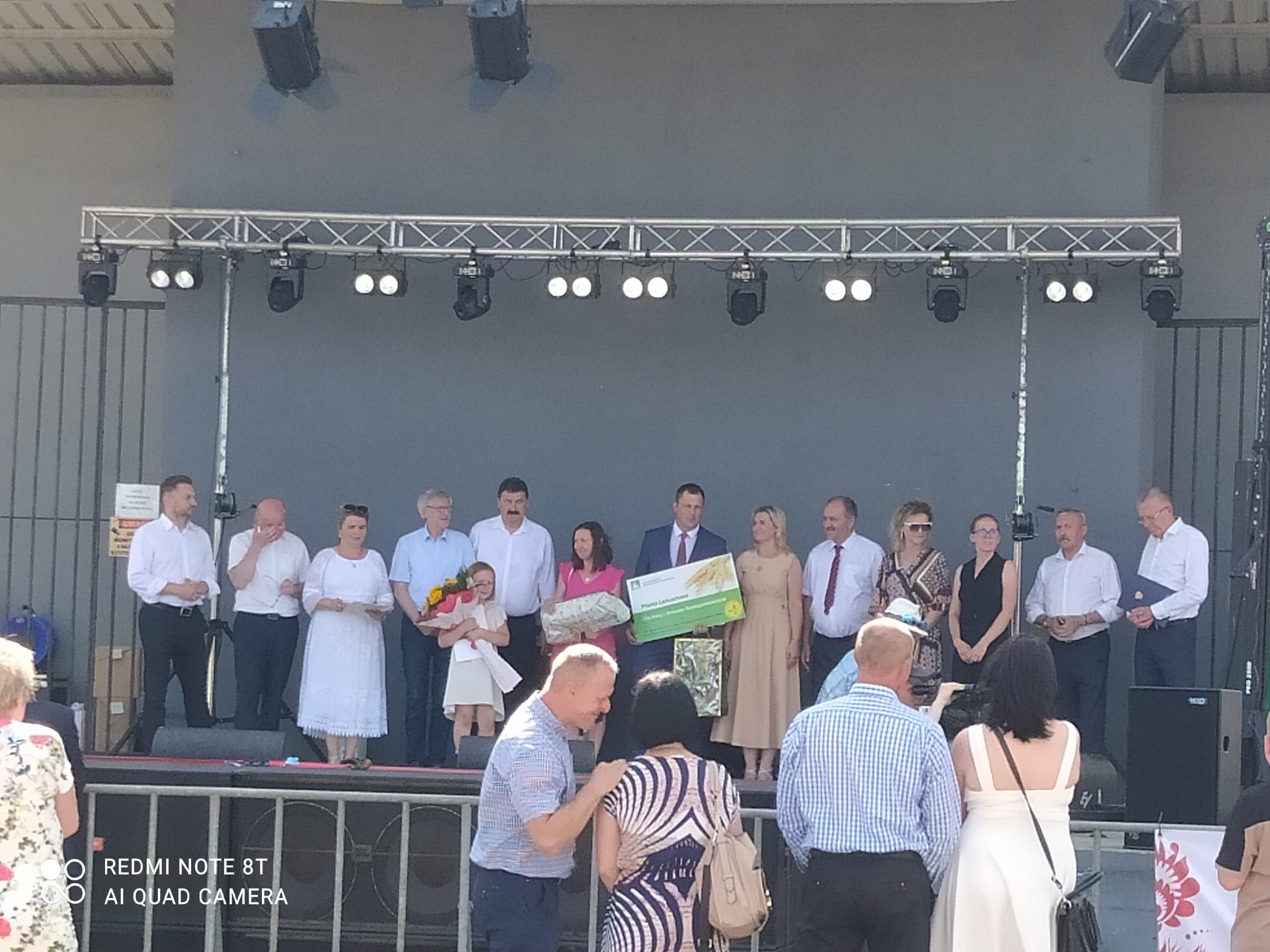 Grupa osób stoi na scenie.