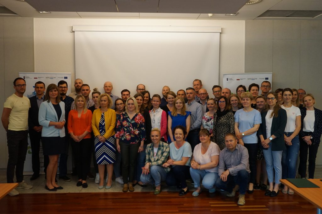 Duża grupa ludzi stojących na tle ściany.