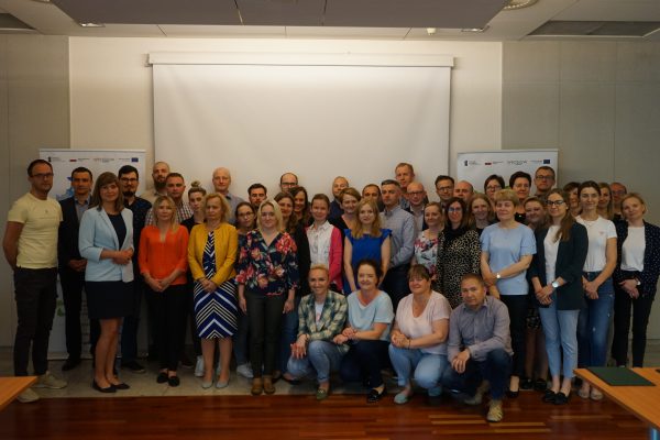 Duża grupa ludzi stojących na tle ściany.