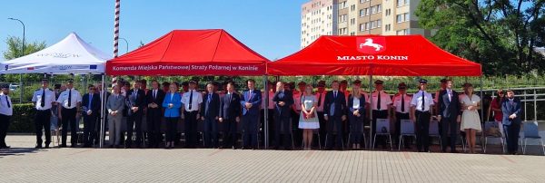 Grupa zaproszonych gości stoi pod namiotami.