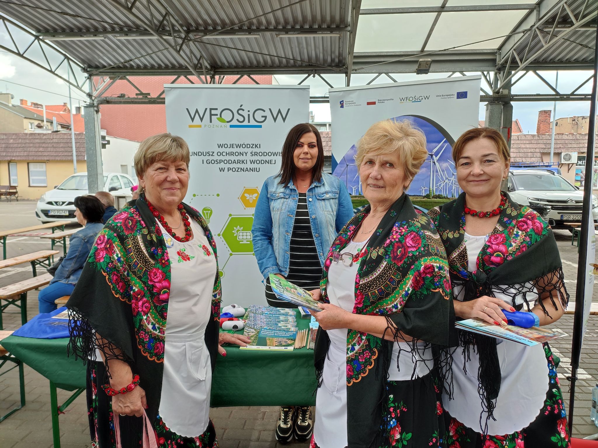 4  osoby stoją przy stoisku w trakcie festynu.