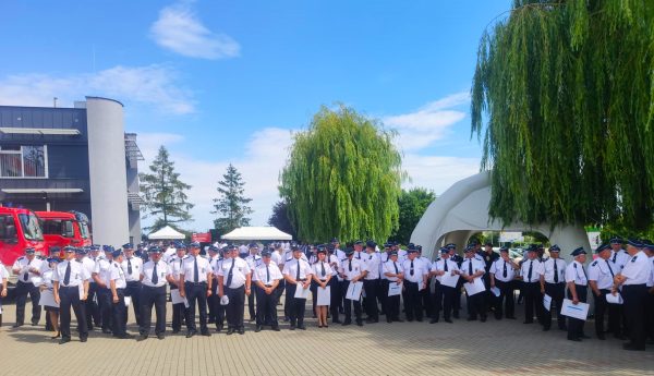 Strażacy stoją na świeżym powietrzu.