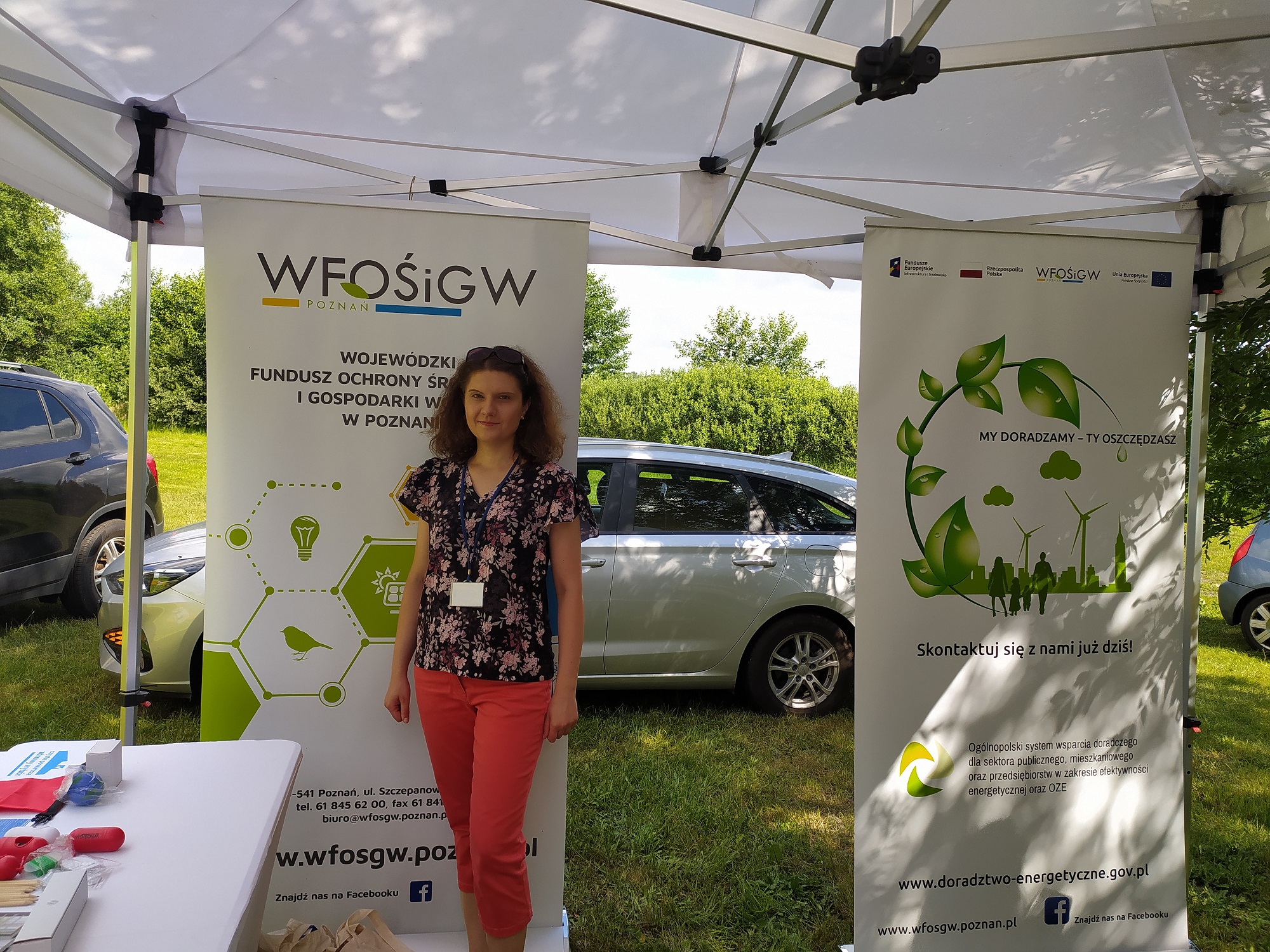 1 osoba stoi przy stoisku wystawienniczym podczas festynu.