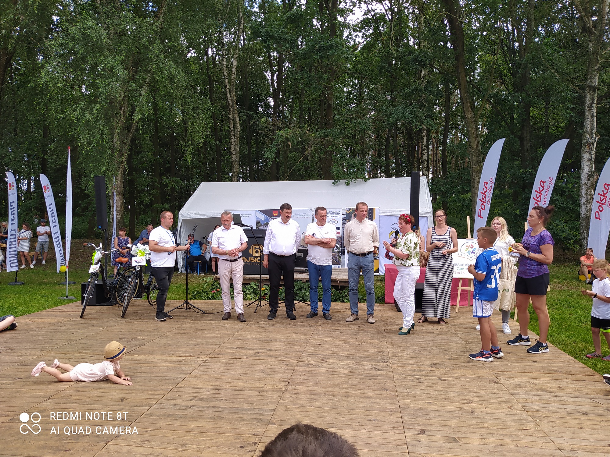 Grupa osób stoi na scenie podczas festynu.