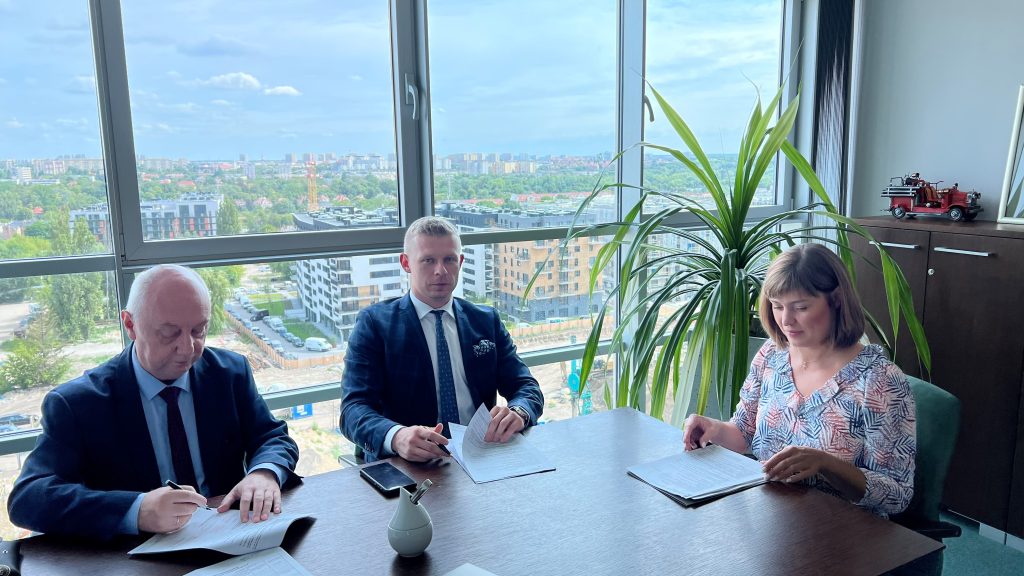 3 osoby siedzą przy stole.