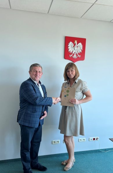 2 osoby stoją przy ścianie i podają sobie dłonie.