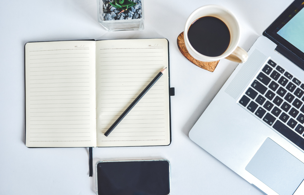 Biurko, a na nim notes, laptop i kawa.