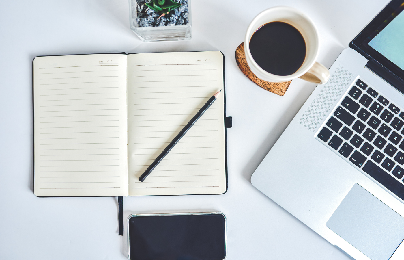 Biurko, a na nim notes, laptop i kawa.