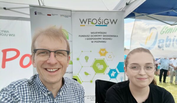 2 osoby na stoisku wystawienniczym podczas festynu.