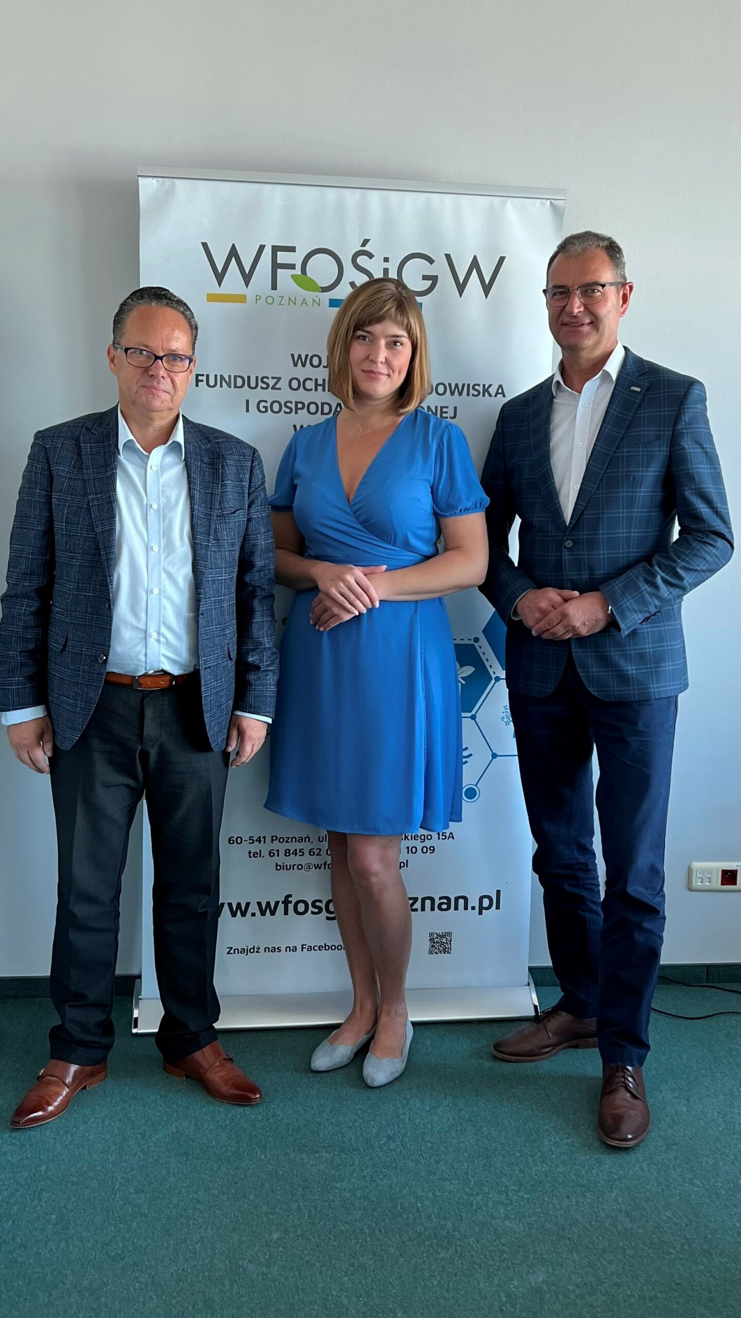 3 osoby stoją na tle ściany.