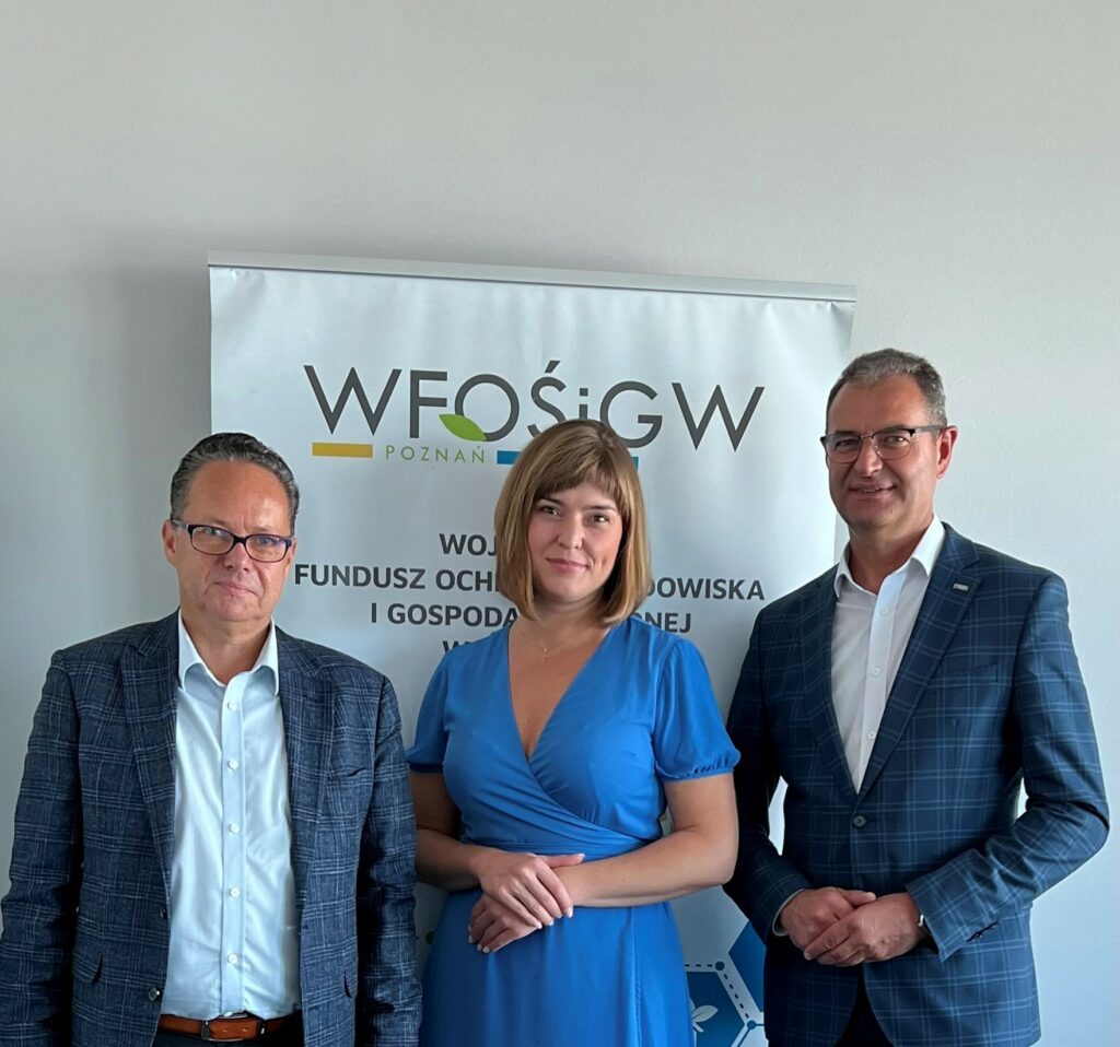 3 osoby stoją na tle ściany.