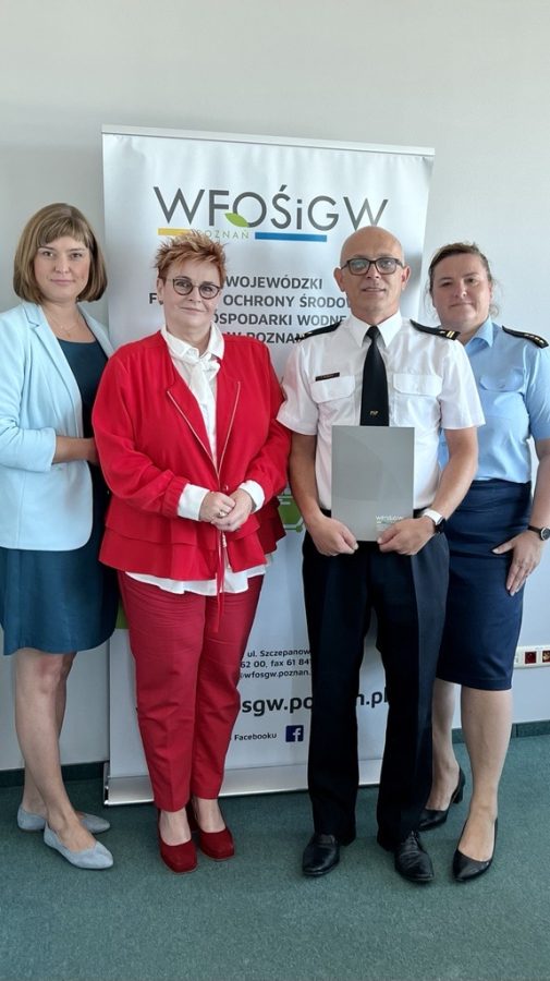 4 osoby stoją na tle ściany.