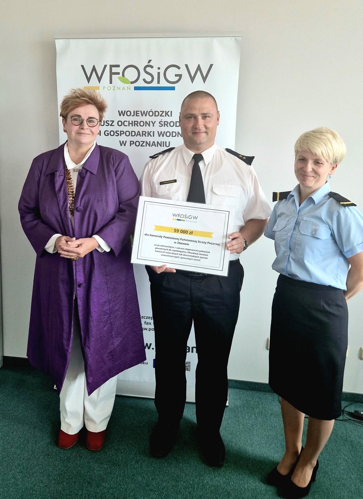 3 osoby stoją na tle ściany.