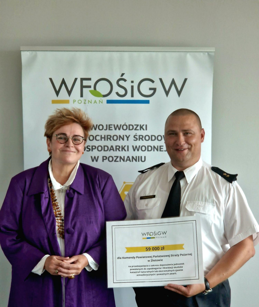 2 osoby stoją na tle ściany.