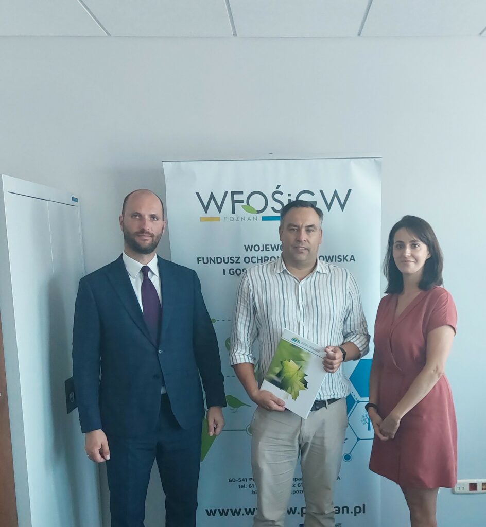 3 osoby stoją na tle ściany.