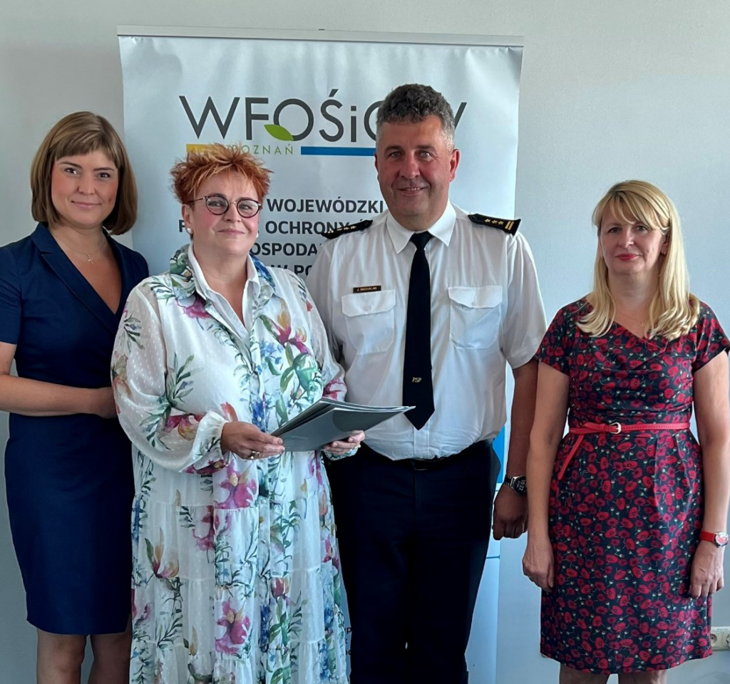 4 osoby stoją na tle ściany.