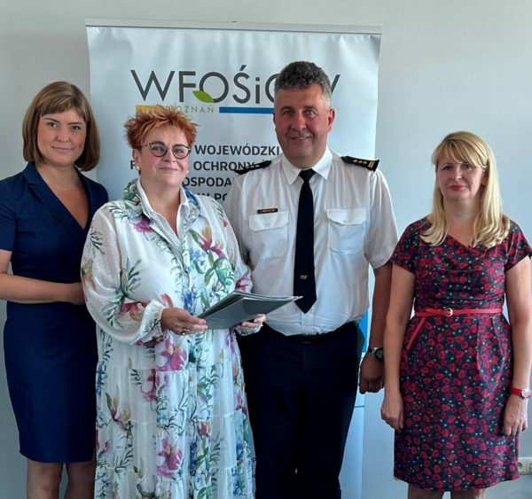 4 osoby stoją na tle ściany.