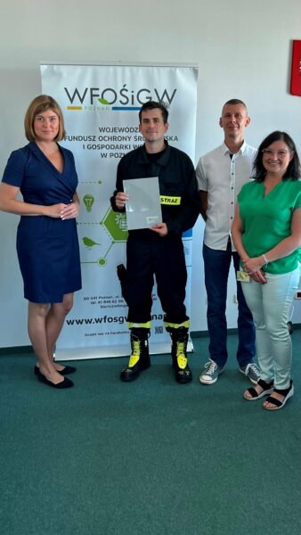 4 osoby stoją na tle ściany.