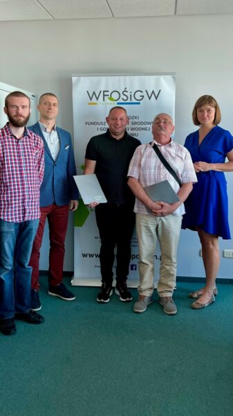 5 osób stoi na tle ściany.