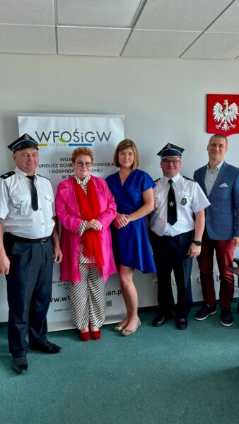 5 osób stoi na tle ściany.