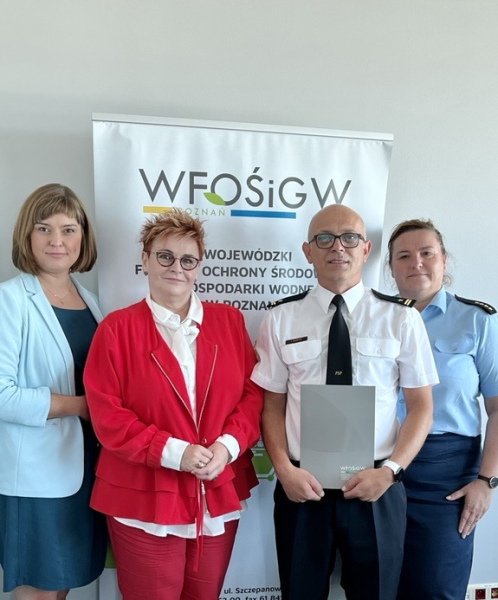 4 osoby stoją na tle ściany.