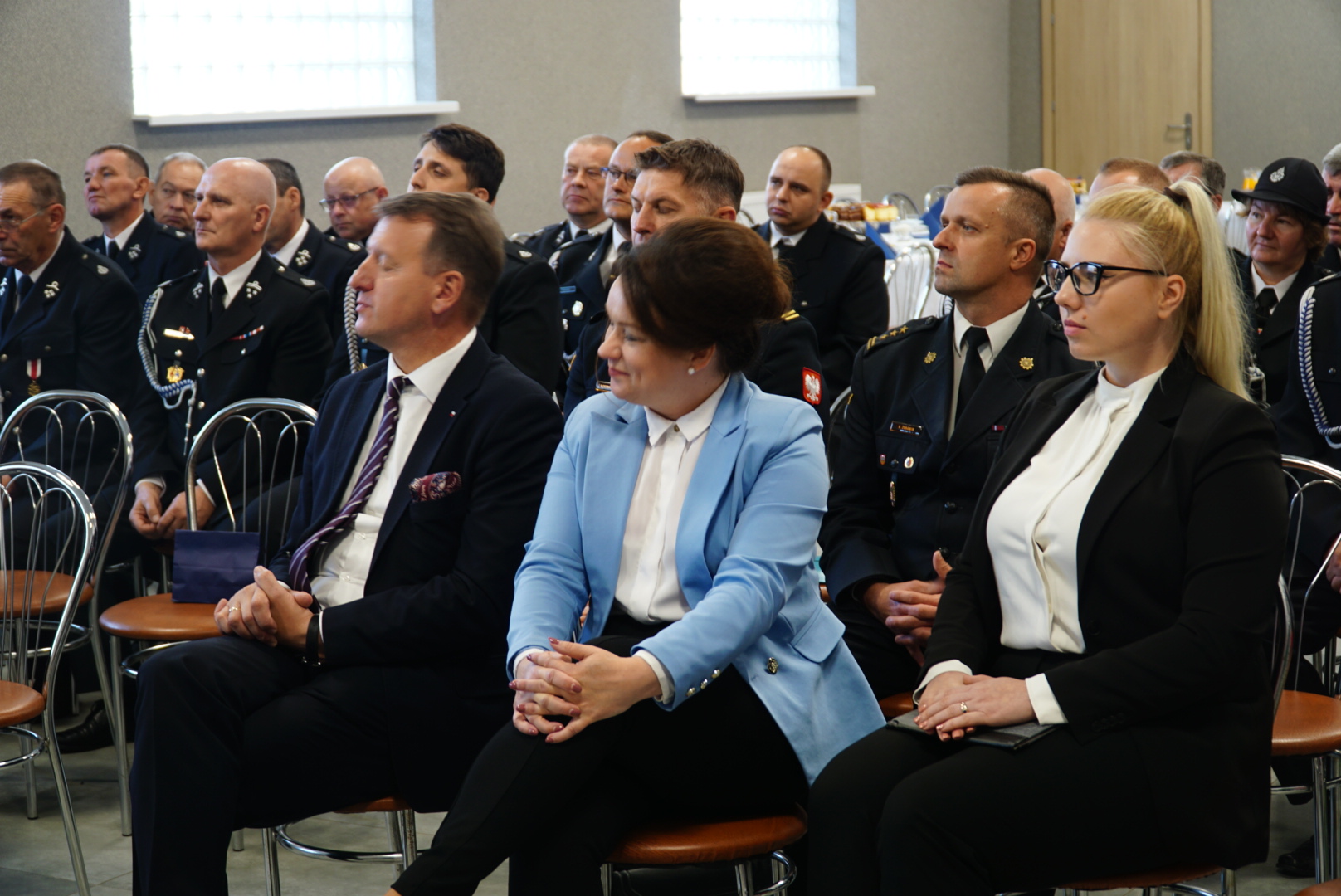 Duża grupa ludzi siedzi w pomieszczeniu na krzesłach.