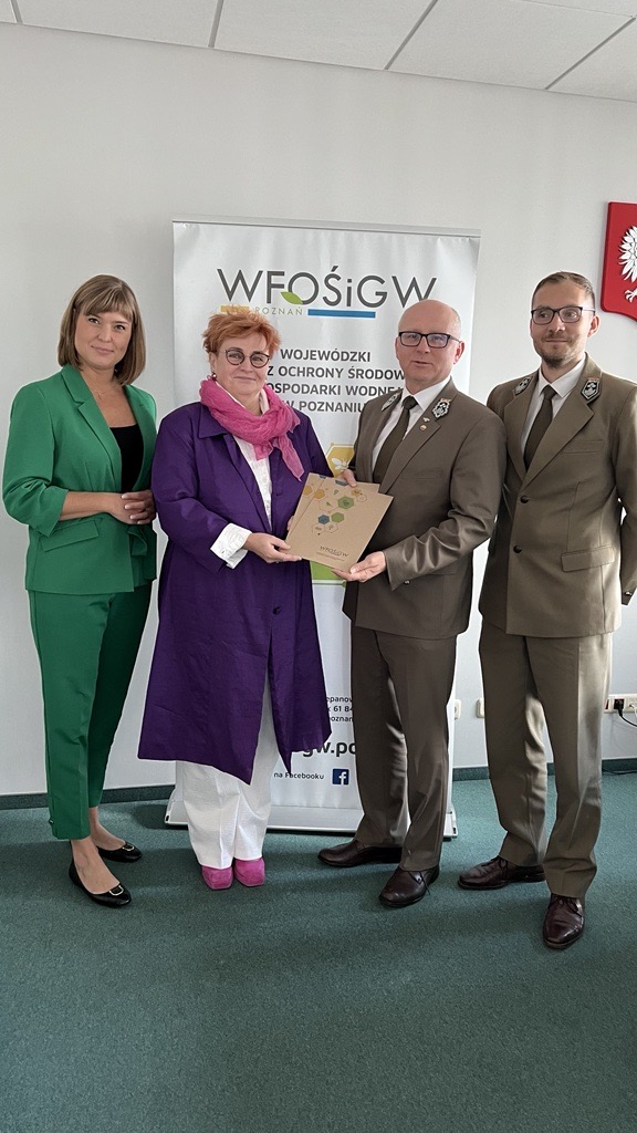 4 osoby stoją na tle ściany.