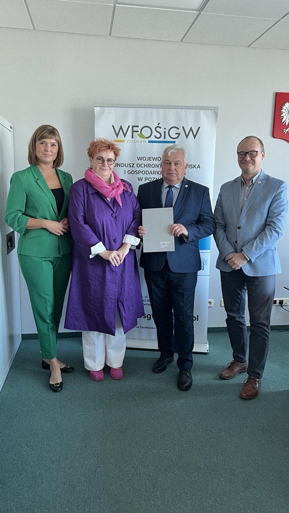 4 osoby stoją na tle ściany.