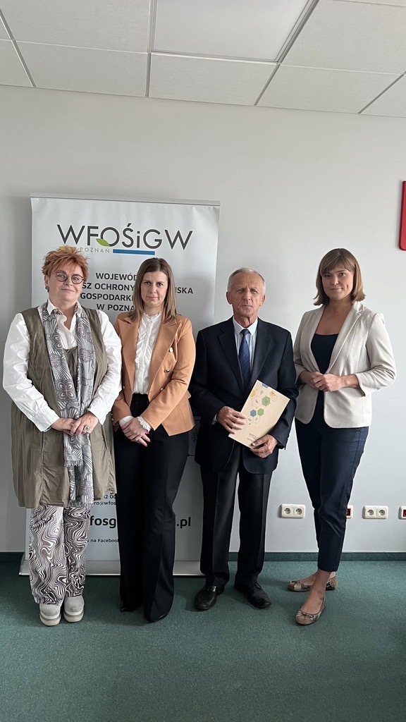 4 osoby stoją na tle ściany.