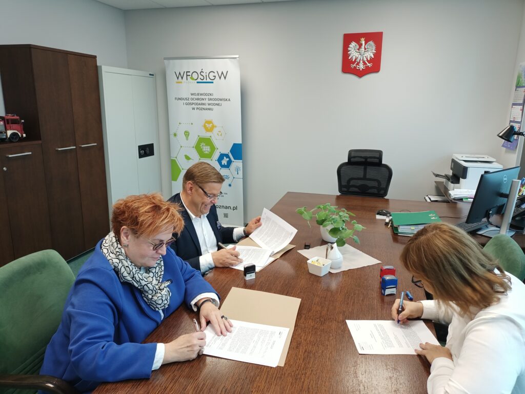 3 osoby siedzą przy stole.