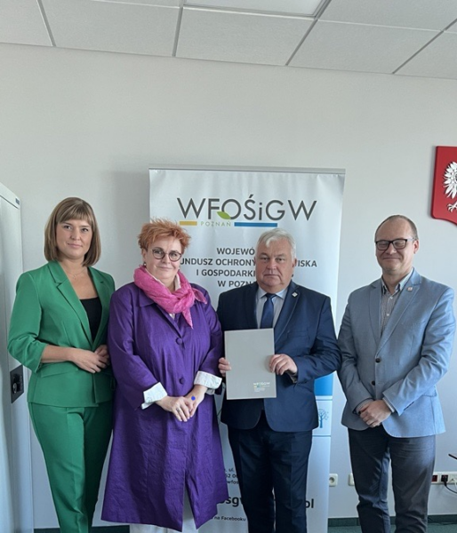 4 osoby stoją na tle ściany.