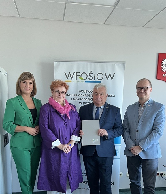 4 osoby stoją na tle ściany.