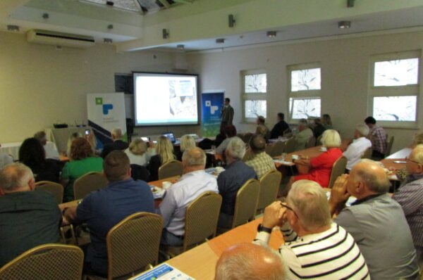 Widok na sale z ludźmi w trakcie trwania konferencji.