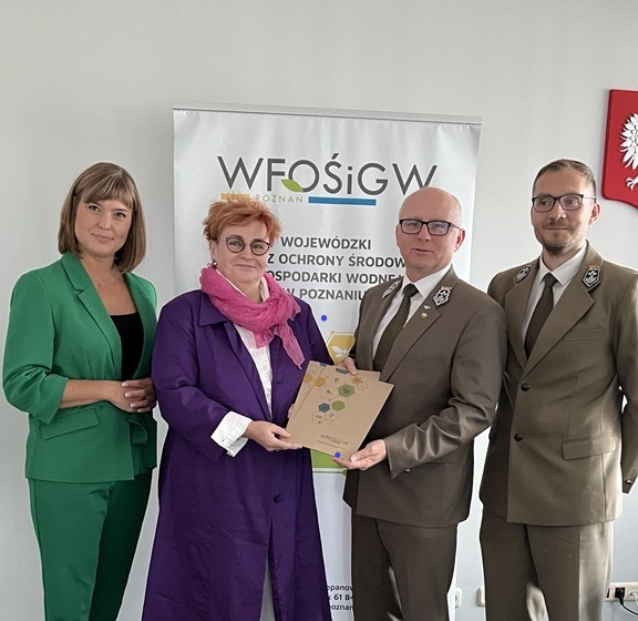 4 osoby stoją na tle ściany.