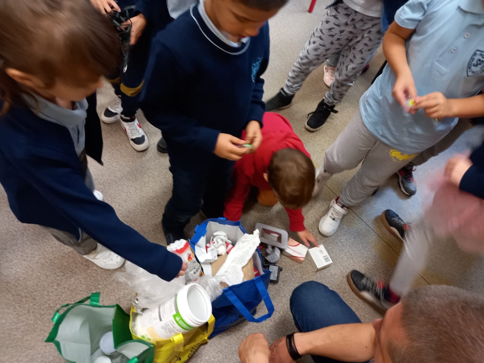 Grupa dzieci segreguje śmieci w sali lekcyjnej.