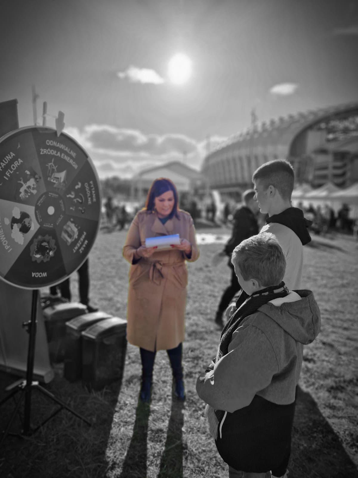 3 osoby stoją przy stoisku na festynie.