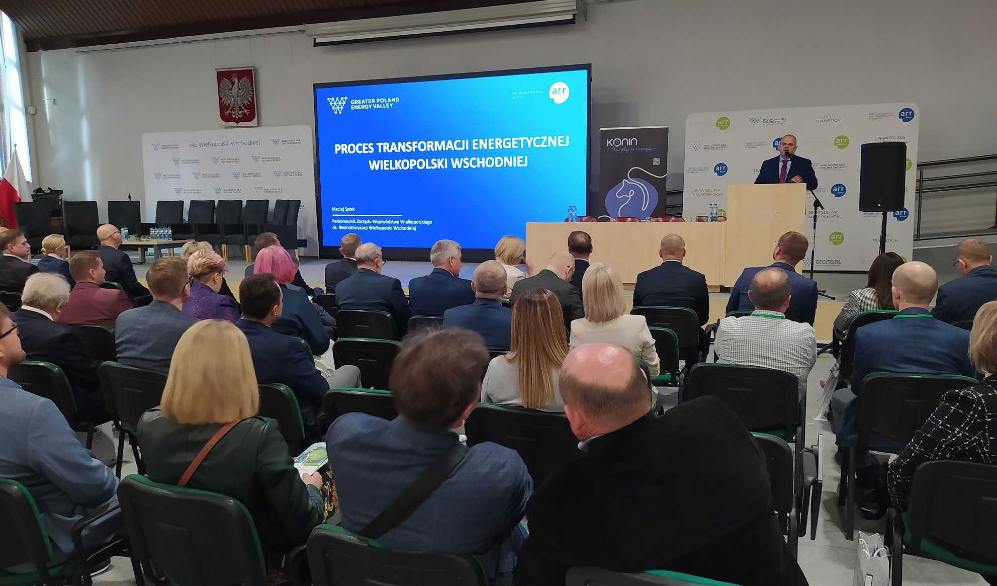 Sala wypełniona ludźmi siedzącymi na krzesłach.