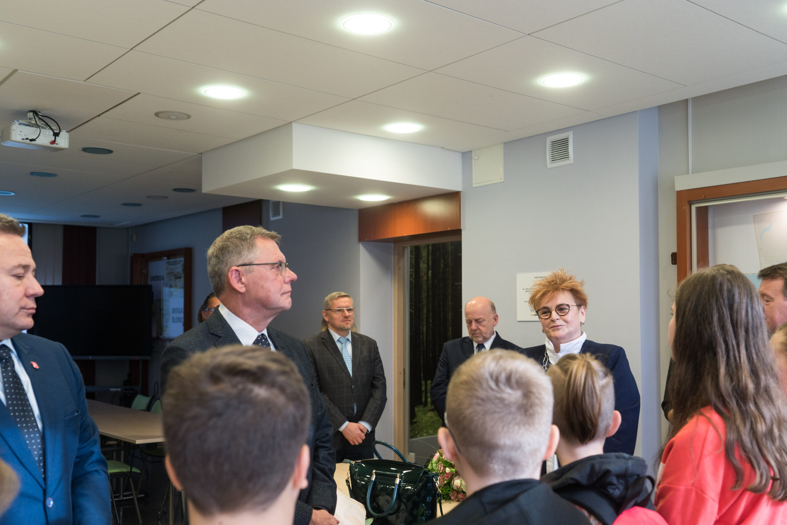 Grupa osób stoi w pomieszczeniu.