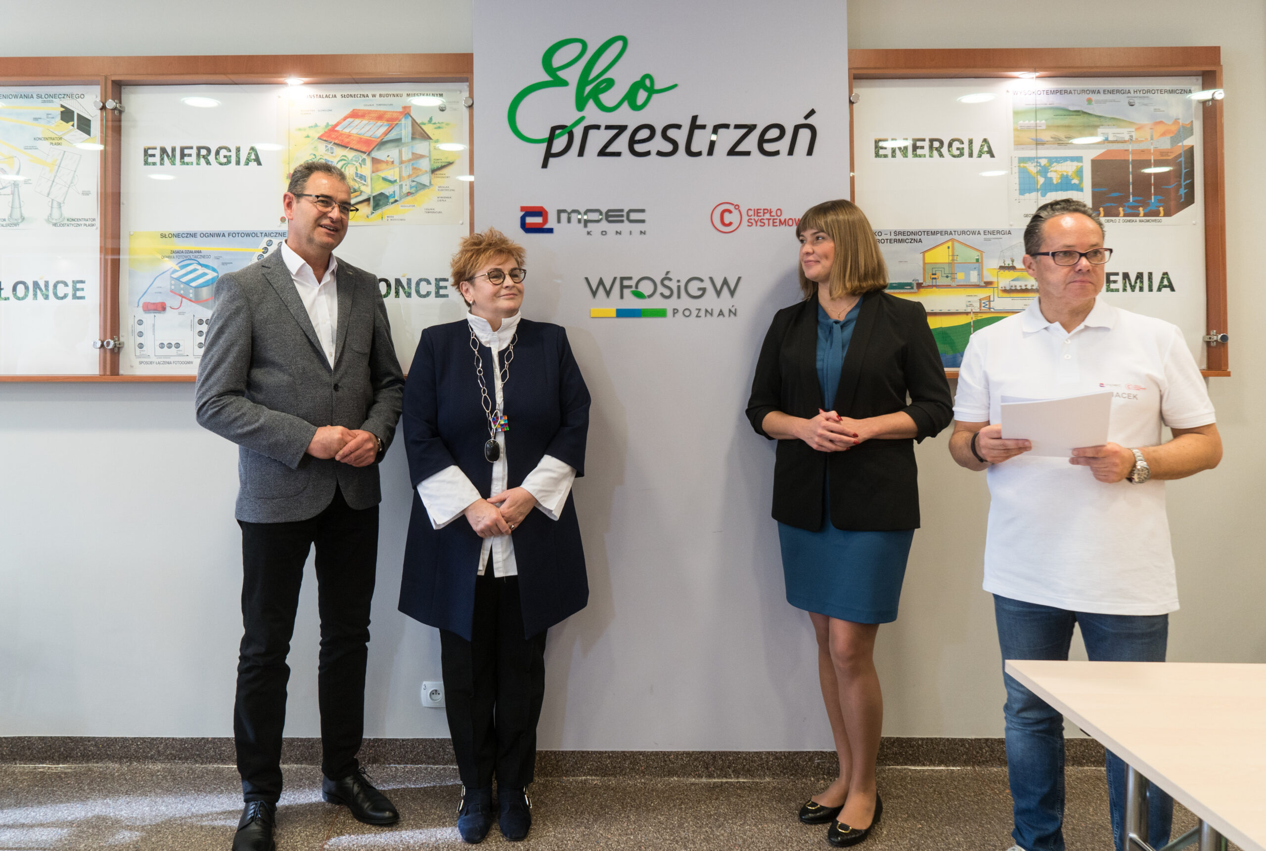 4 osoby stoją na tle ściany.