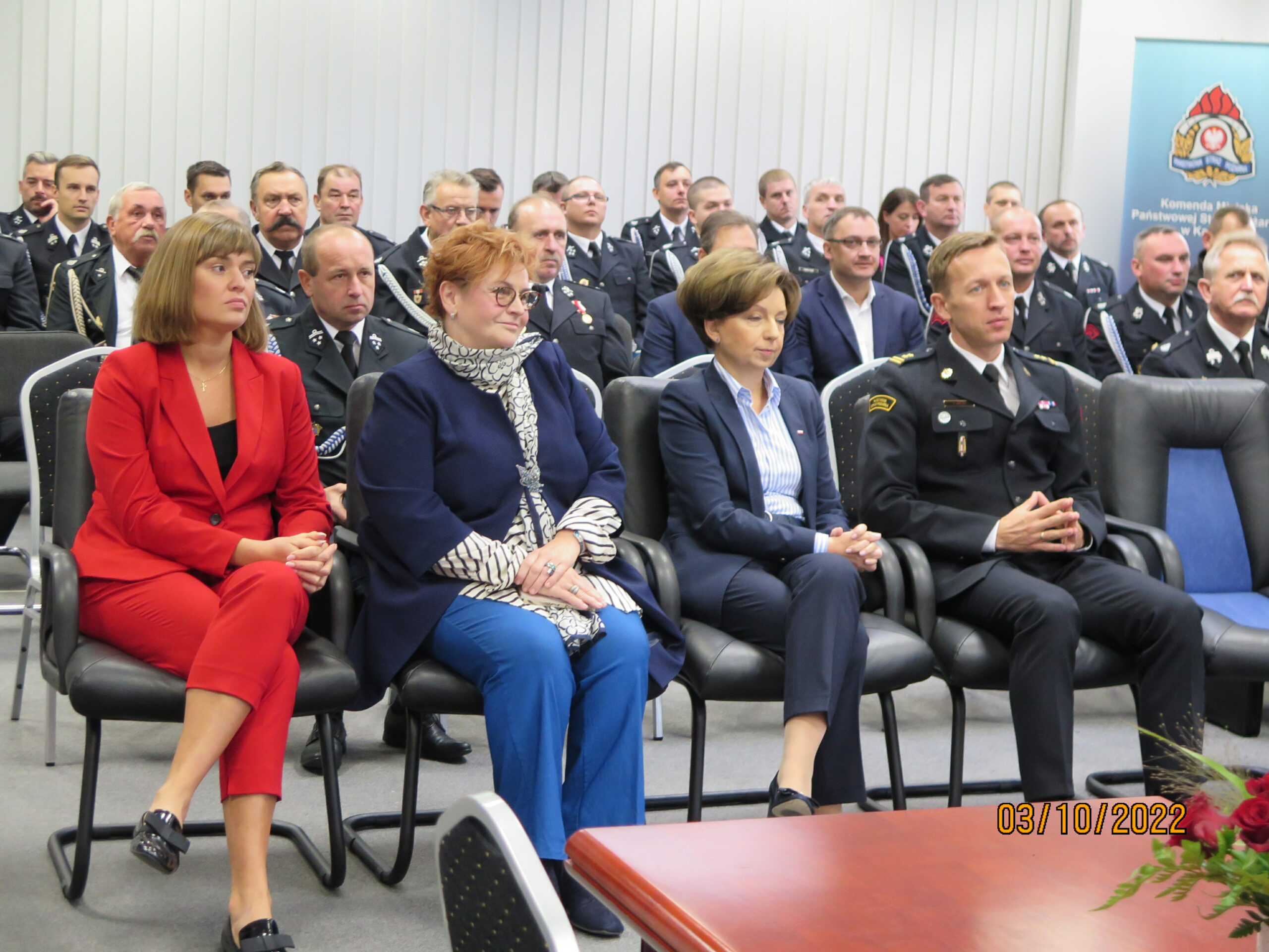 Ludzie siedzą na krzesłach na sali.