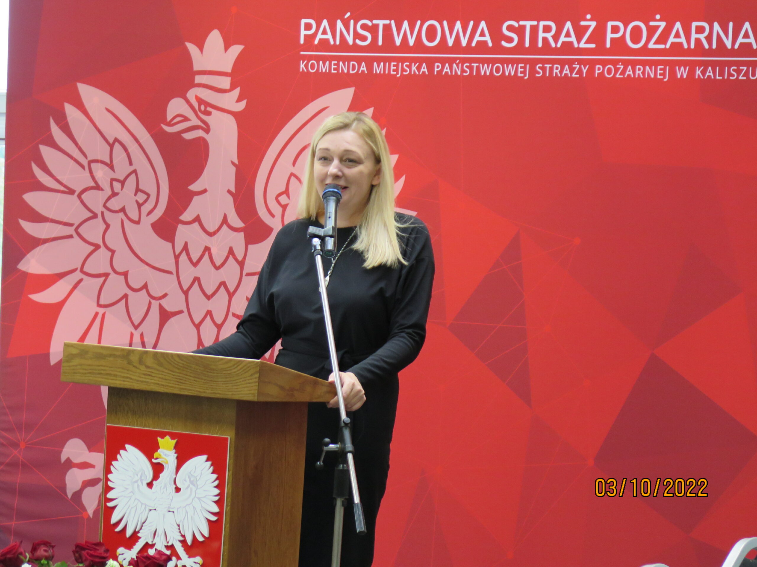 1 osoba stoi na tle ściany.