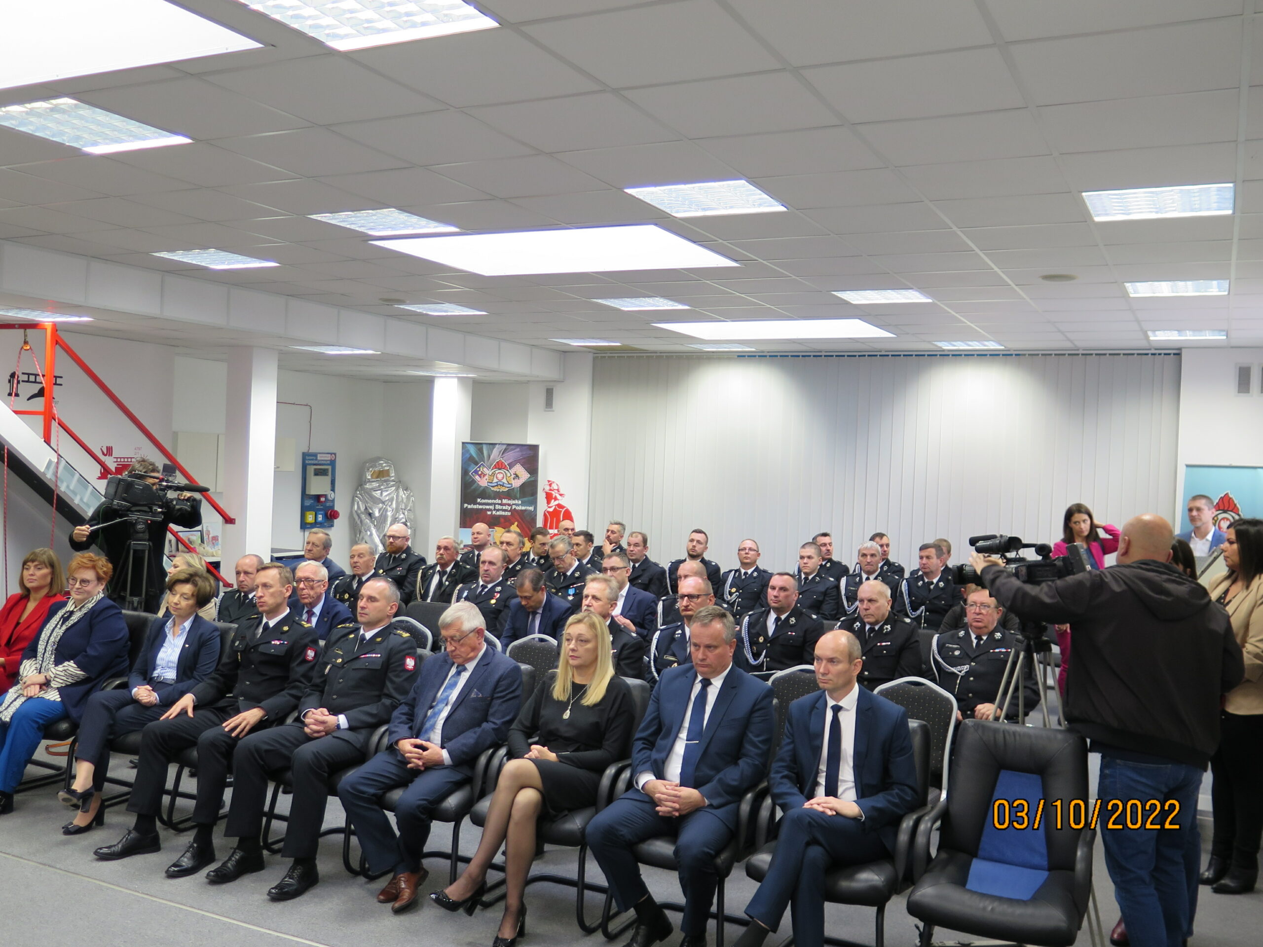 Ludzie siedzą na krzesłach na sali.