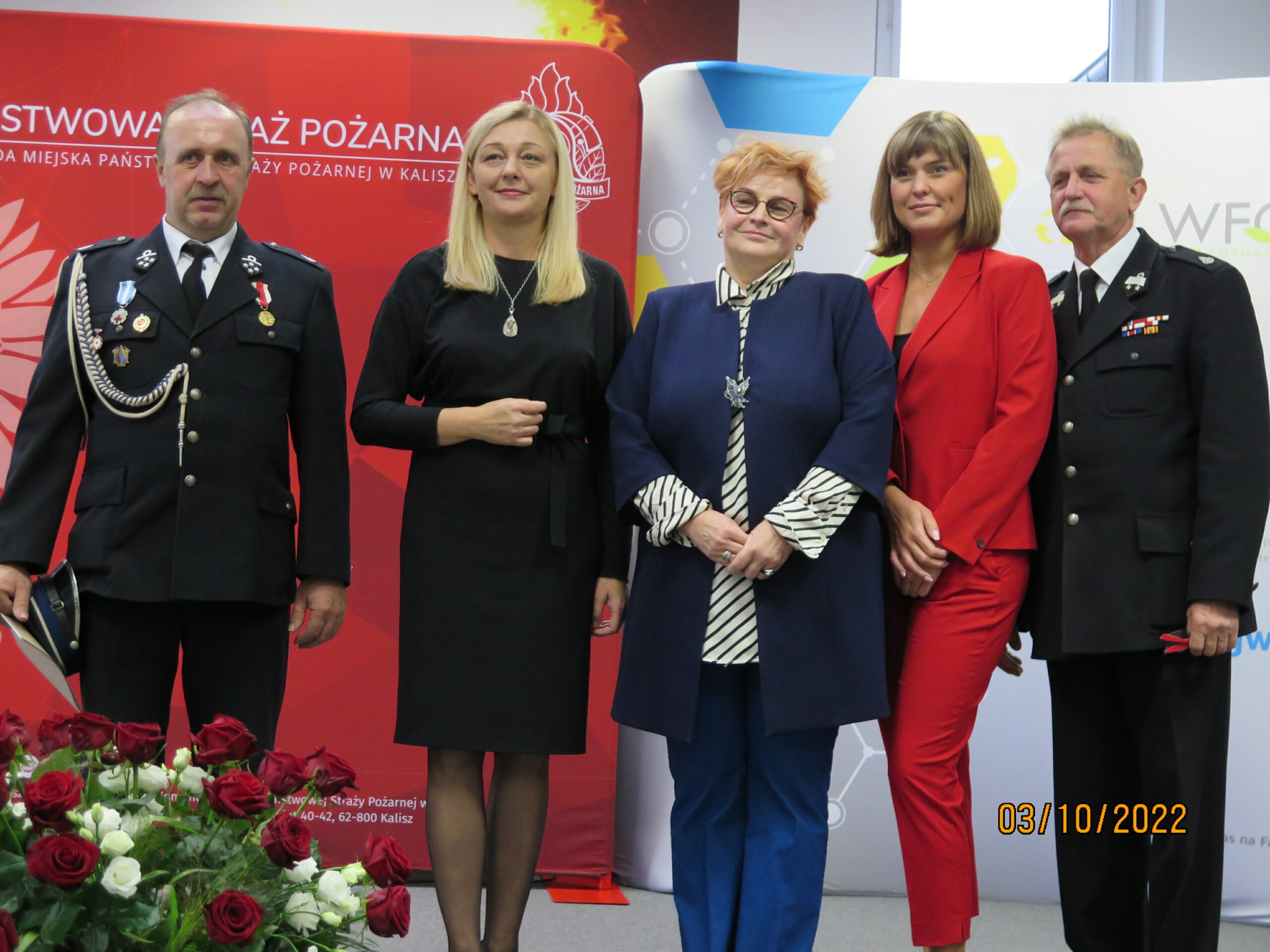 5 osób stoi na tle ściany.