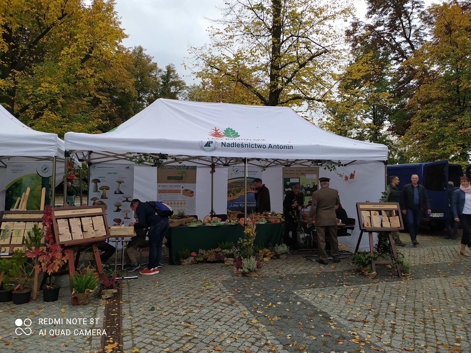 4 osoby stoją przy stoiskach podczas festynu.