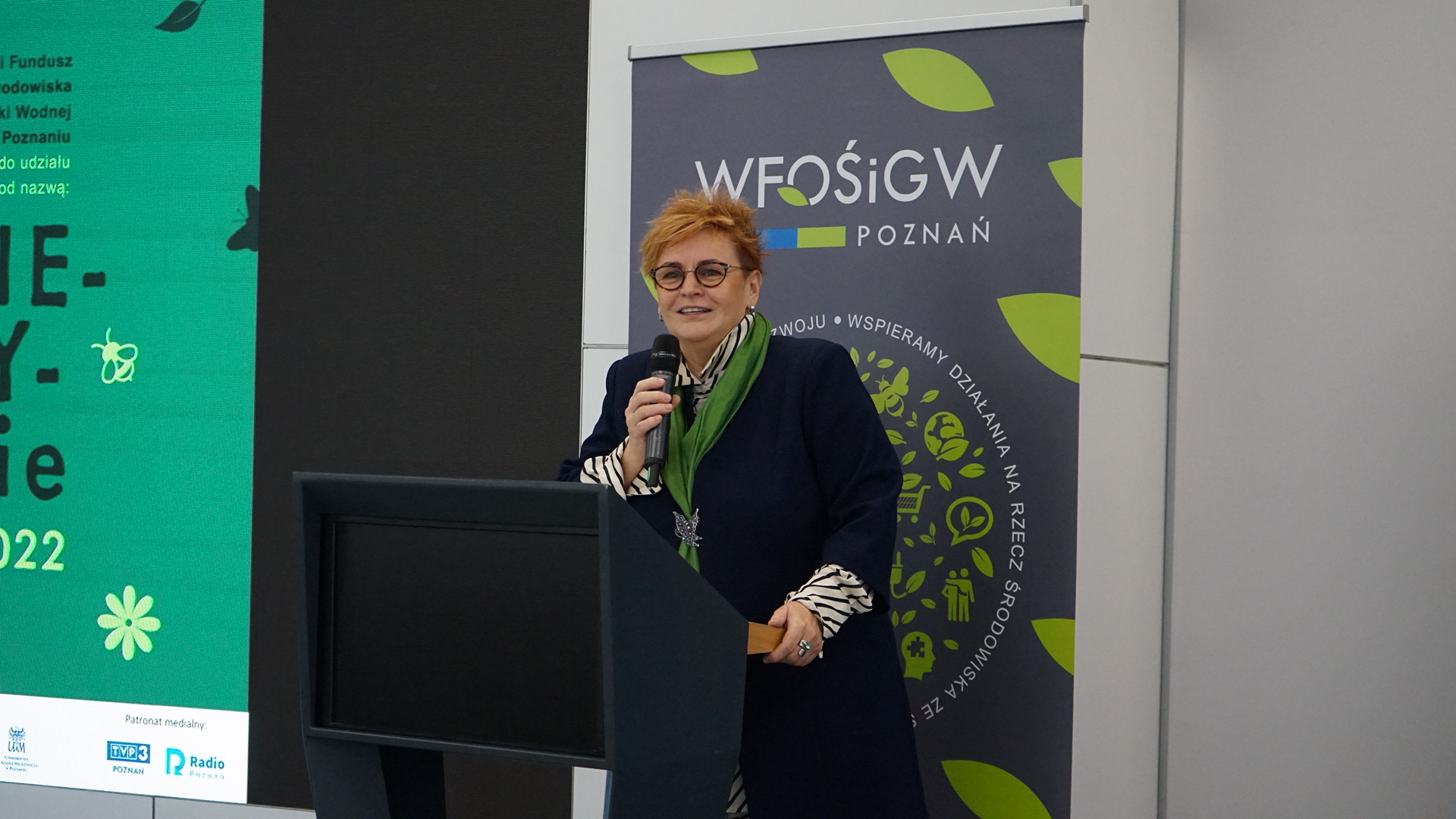 Jedna osoba stoi przy mównicy.