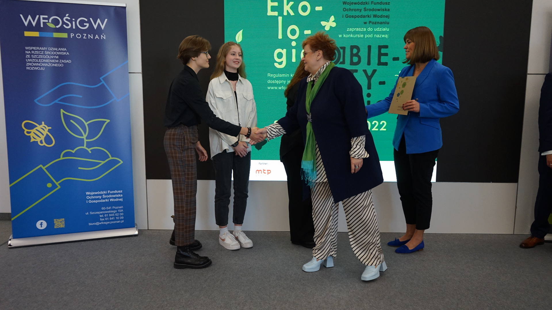 5 osób stoi na tle ściany.